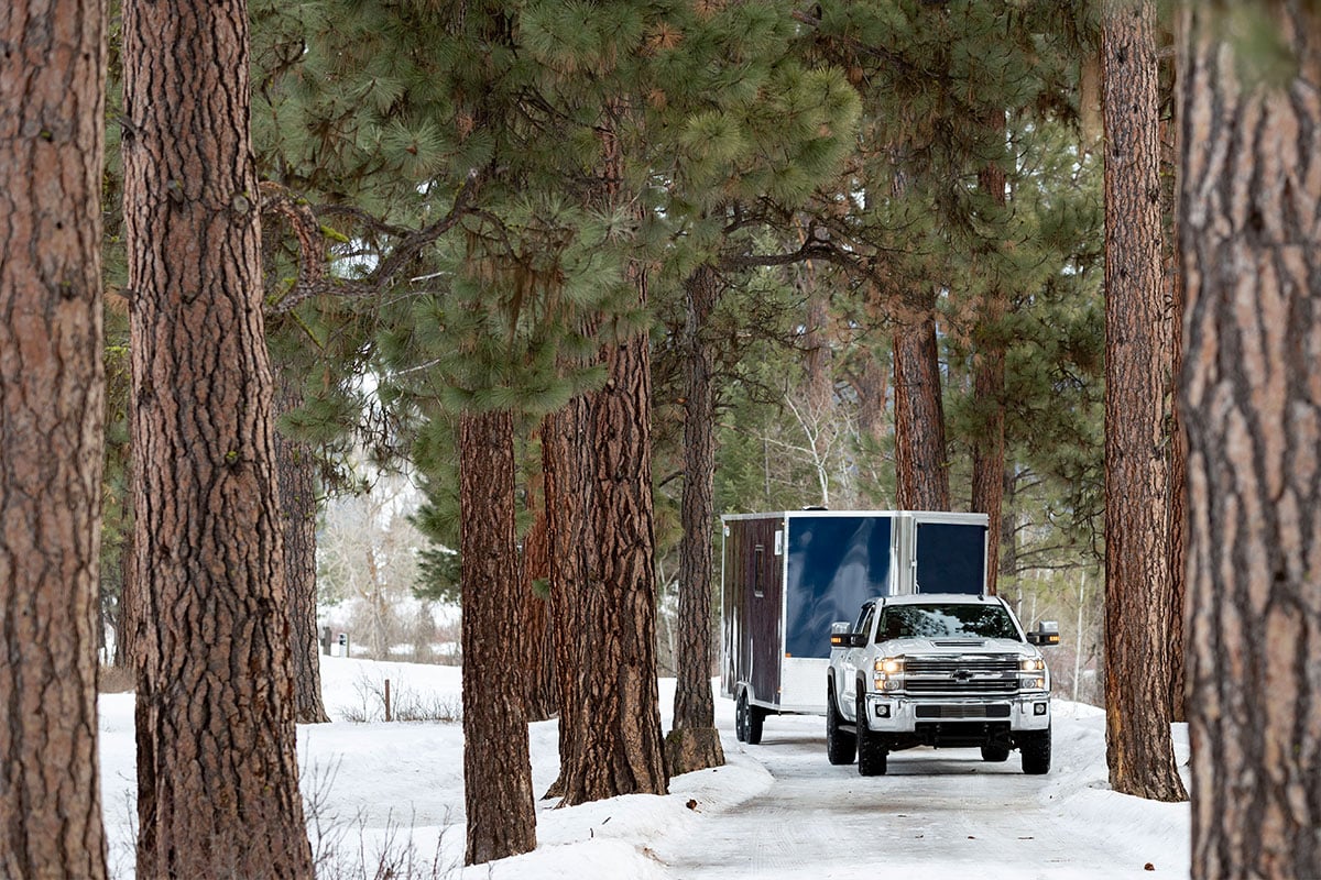 Truck towing an aluminum All-Sport trailer through the trees in Montana 