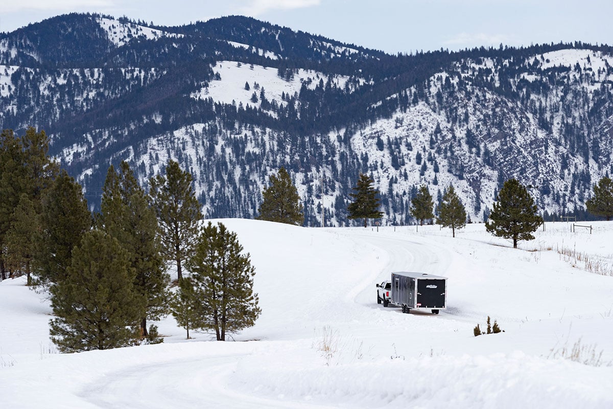 All-Sport enclosed snow trailer towed by a pickup truck across a snowy Montana landscape