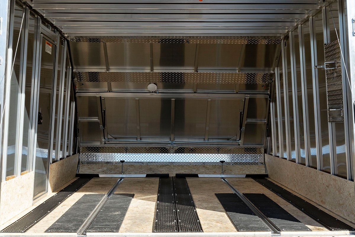 Full interior view of empty Crossover trailer: track mats, ski guides, tie-down bars, dome light