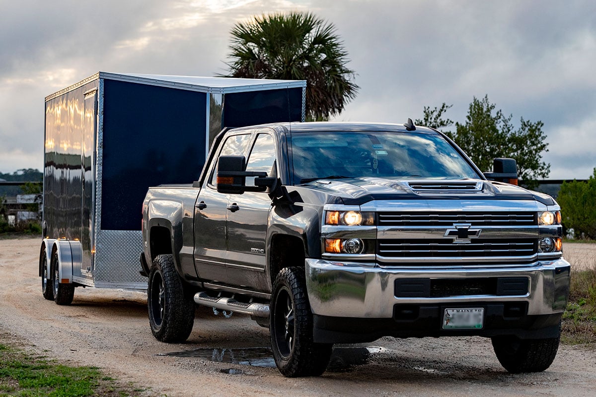 Enclosed ATV trailer towed by a pickup truck in Florida at dusk