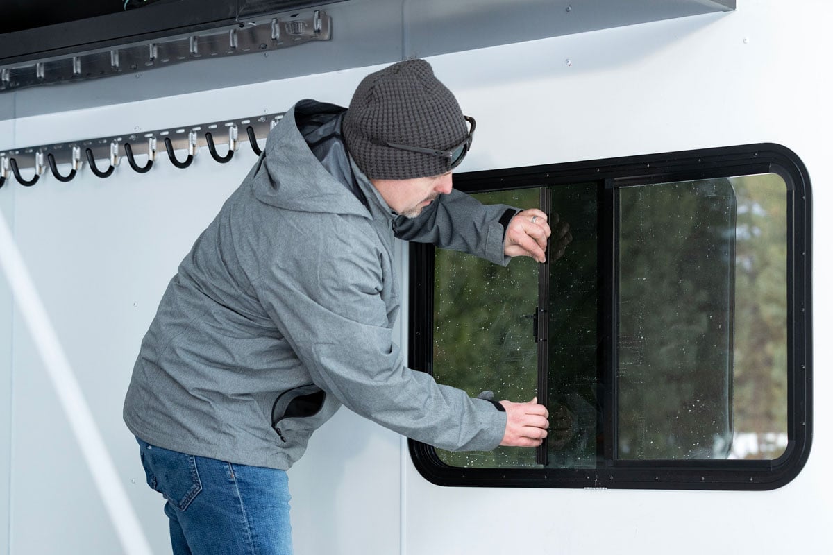 Inside an Elevation Series snowmobile trailer by ALCOM featuring a sliding window and coat hooks