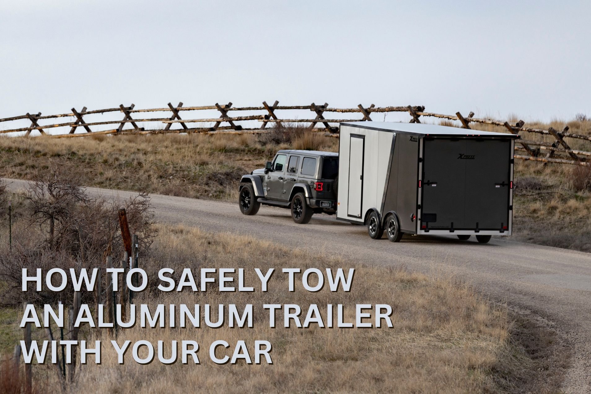 A gray Jeep tows a 7'-wide ALCOM aluminum enclosed cargo trailer on a Montana road with hills and fences in the background