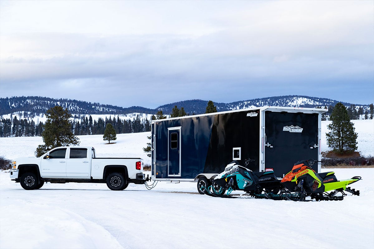 Inline aluminum snowmobile trailer from ALCOM parked at a scenic Montana spot