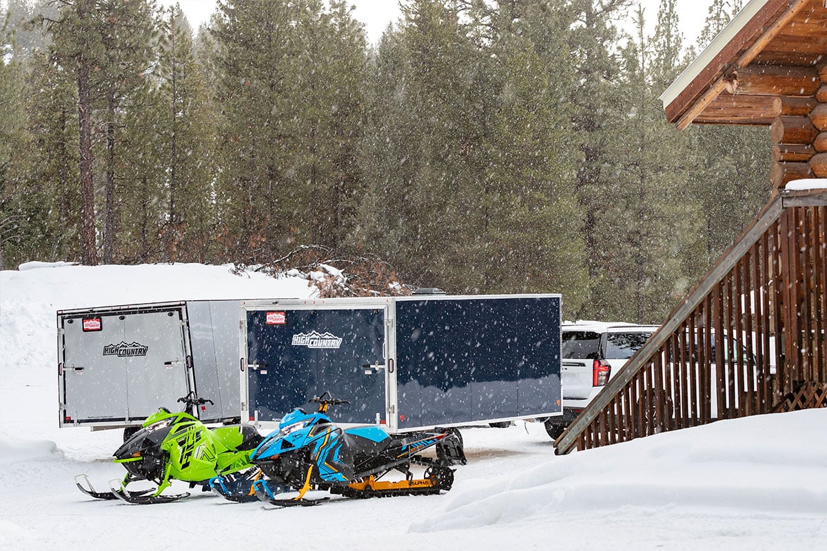 Two High Country aluminum snowmobile trailers parked at a cabin in Seeley Lake, Montana during winter
