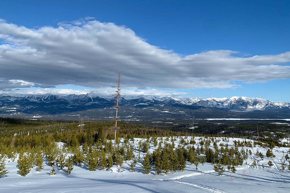 Stunning views of distant mountains and a snowy field while snowmobiling in the Seeley Lake, Montana area