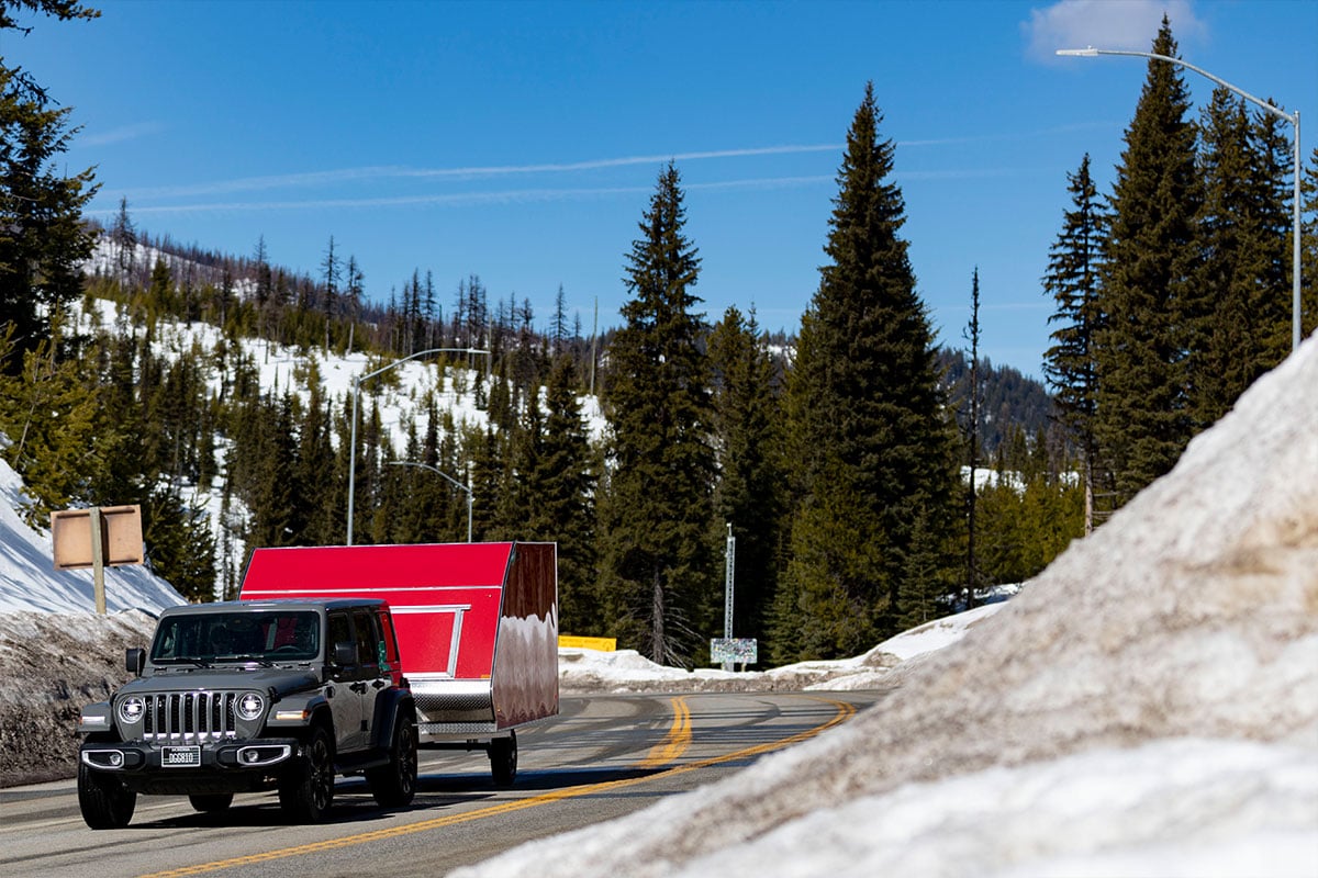 Gray Jeep towing red High Country Crossover aluminum snowmobile trailer at Lolo Pass, Montana