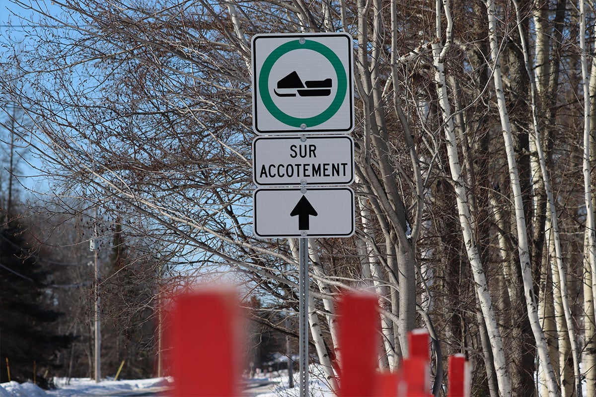 Snowmobile sign in Quebec, Canada, indicating snowmobiles should ride on the shoulder of the road