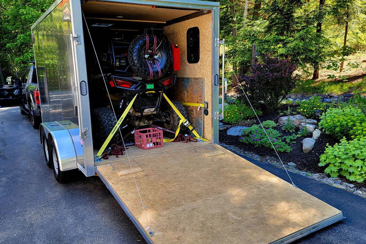 A custom camping setup in a silver enclosed ALCOM trailer, fully loaded.