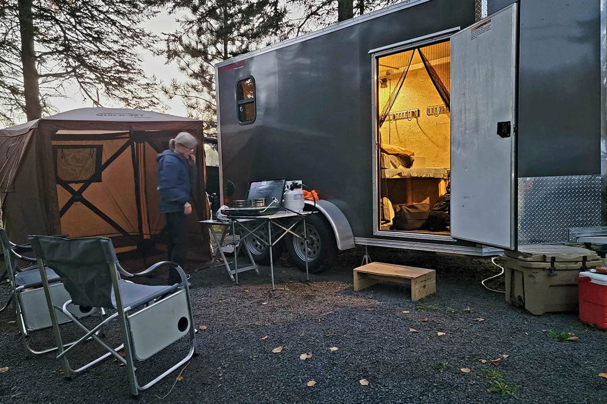 Home away from home - a side by side trailer turned camper, set up with all the essentials at twilight.