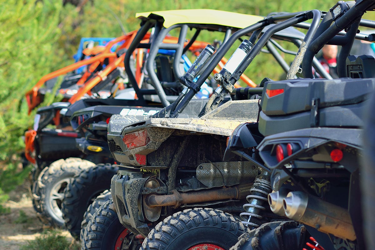 A group of side by sides parked near the trail.