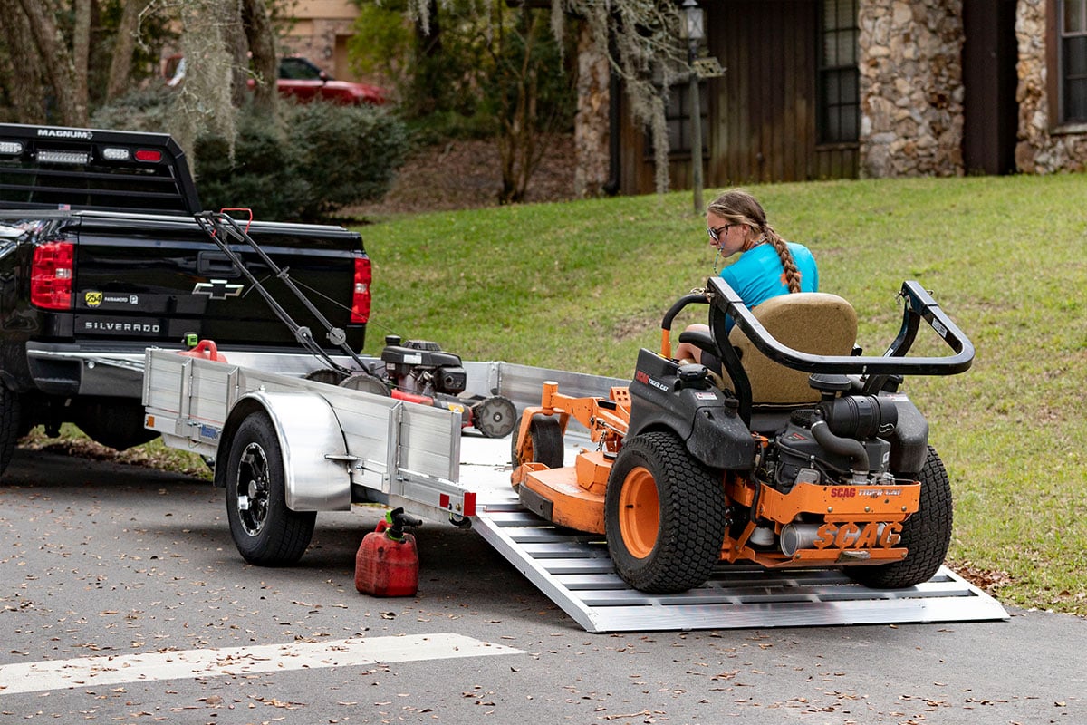 Driving a lawnmower off an open ALCOM landscape trailer using an integrated rear ramp.