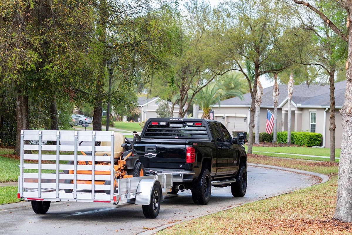 Open aluminum utility trailer loaded with landscape eqiupment.