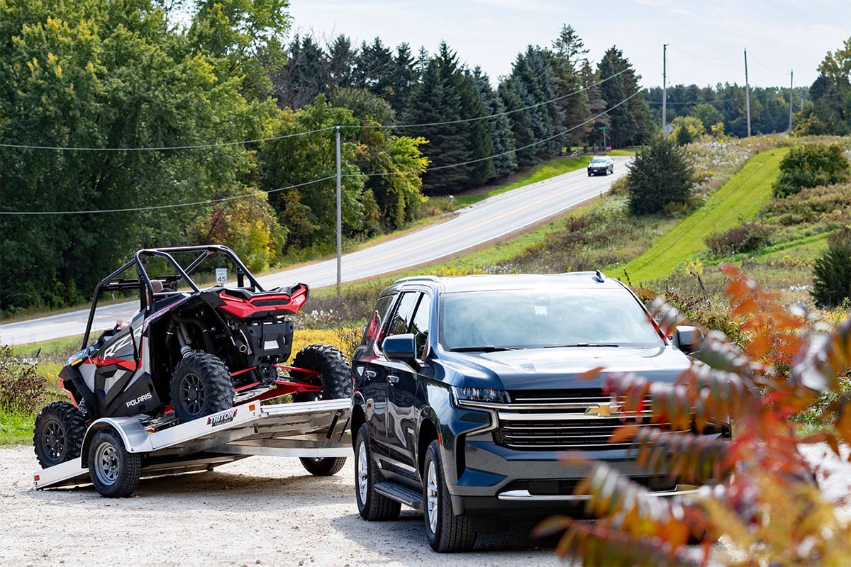 Open tilting aluminum trailer with tilt activated and ATV ready to unload.