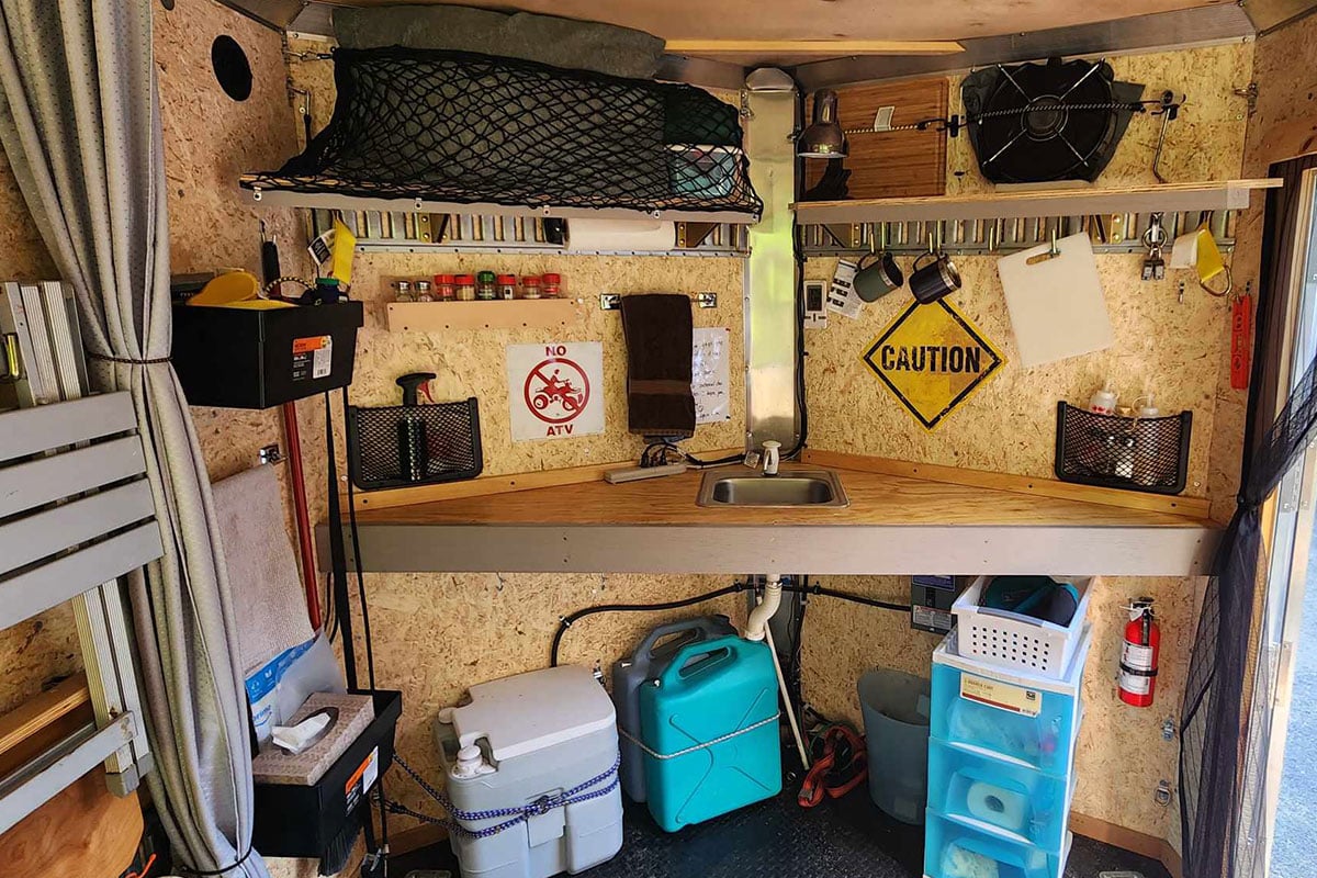 The V-nose area of Ted's aluminum ATV trailer set up with a sink, shelving and storage.