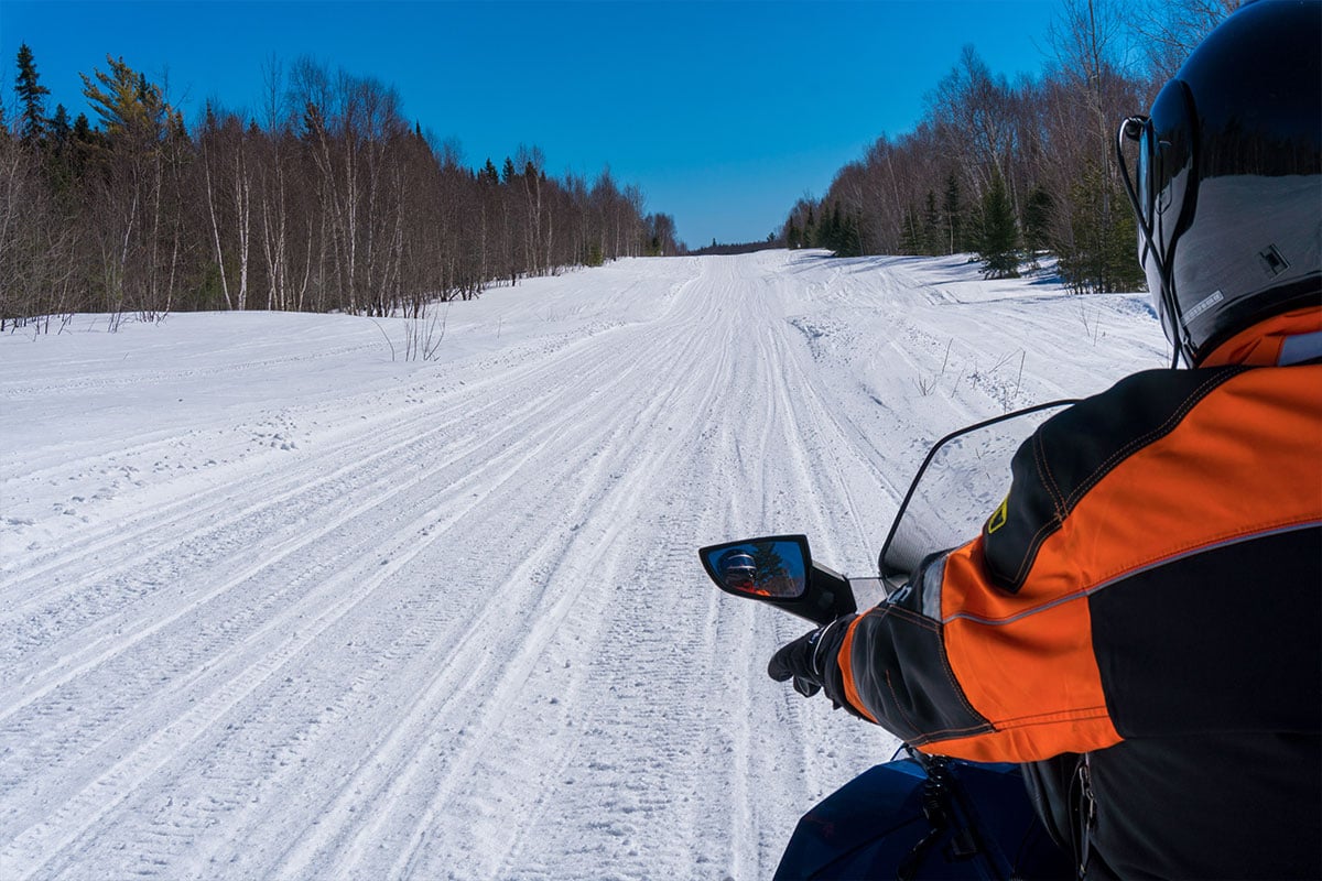 Snowmobile rider stops at the side of a well used trail in Ontario, Canada on a sunny day