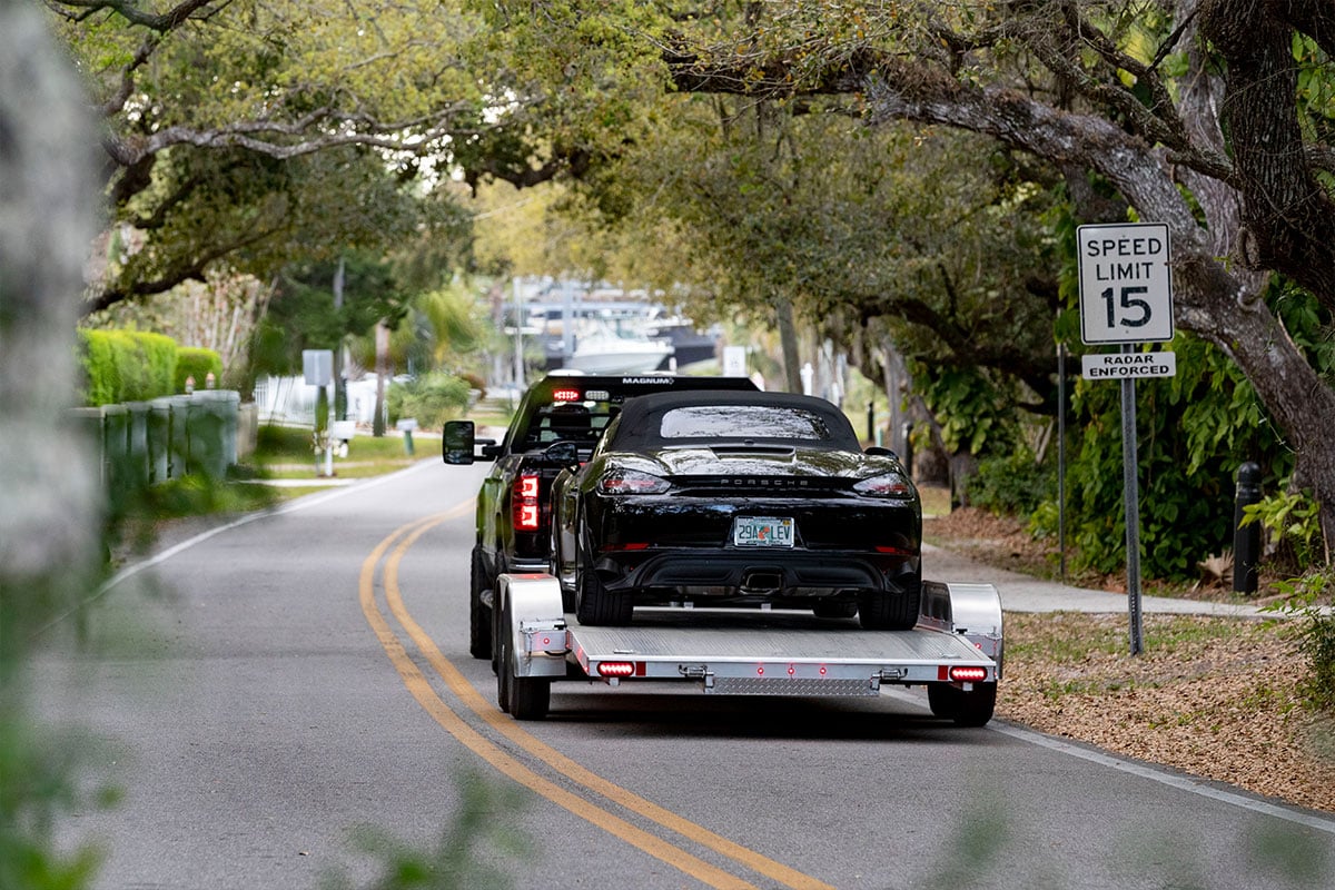 Extruded aluminum deck car trailer from ALCOM on the road with a sports car