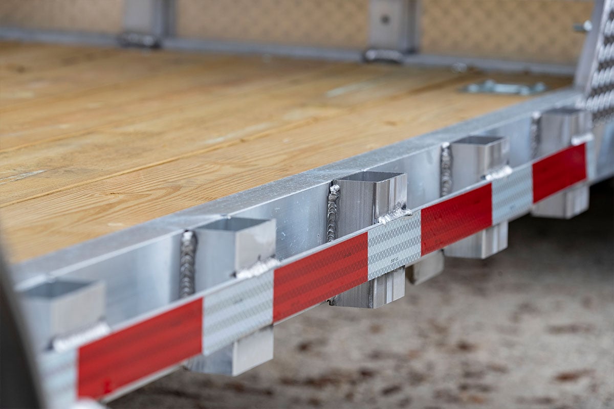 Stake pockets and rub rail on an open wood deck ALCOM aluminum car trailer