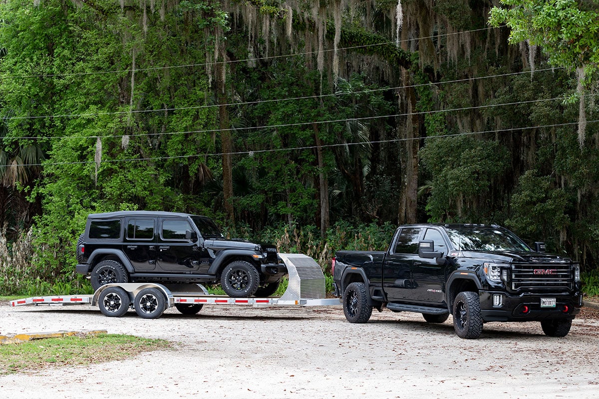 ALCOM open wood deck car trailer with air dam hitched to a pickup truck