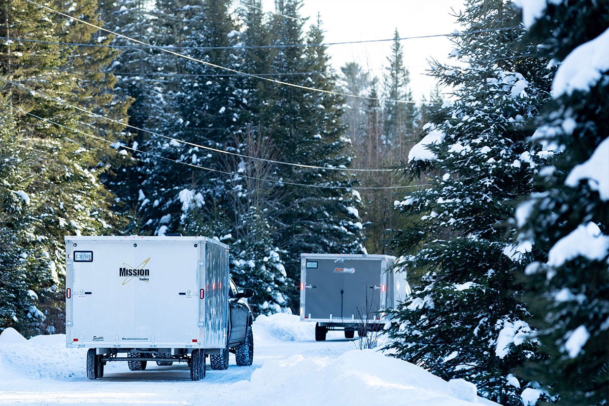 Two ALCOM snow trailers on the road during winter.