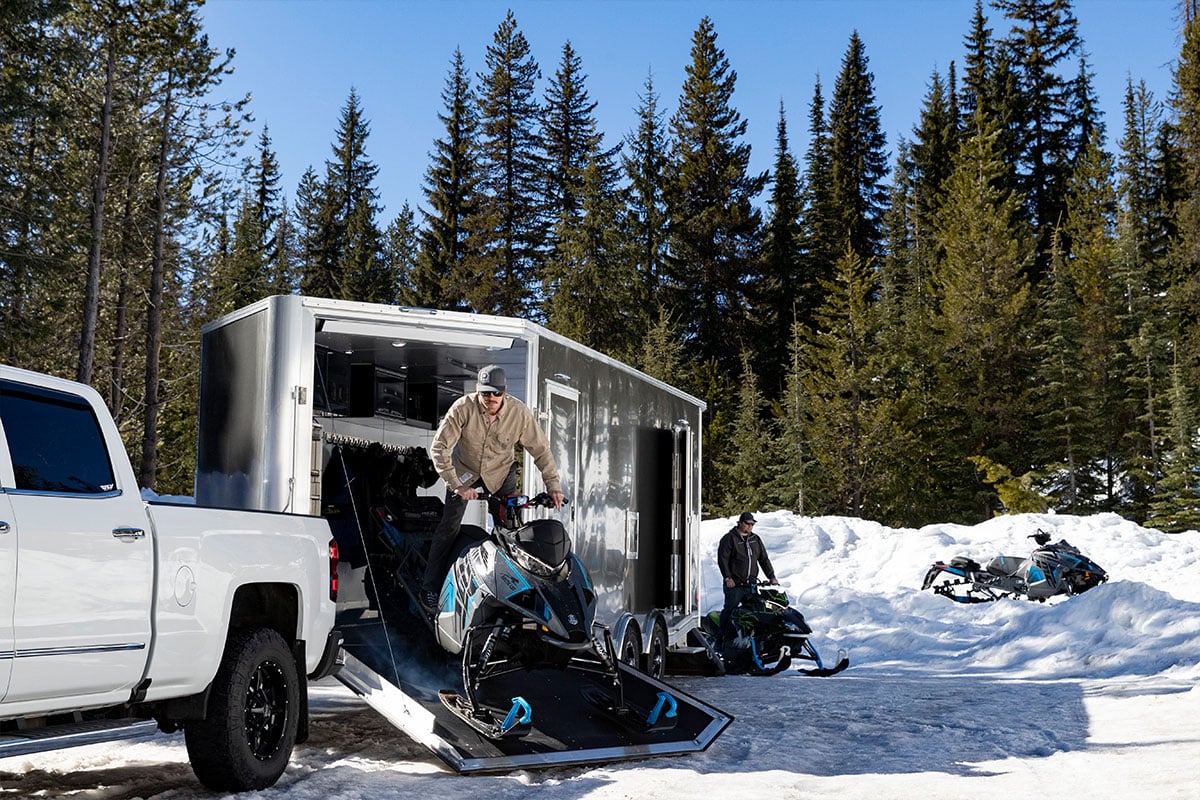 Drive sleds out the front ramp door of an enclosed snow trailer from ALCOM