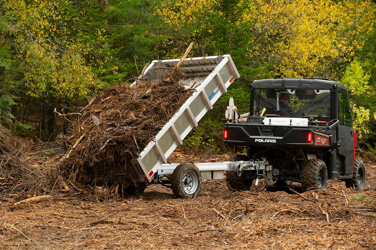 Aluminum homeowner dump trailer unloading brush.