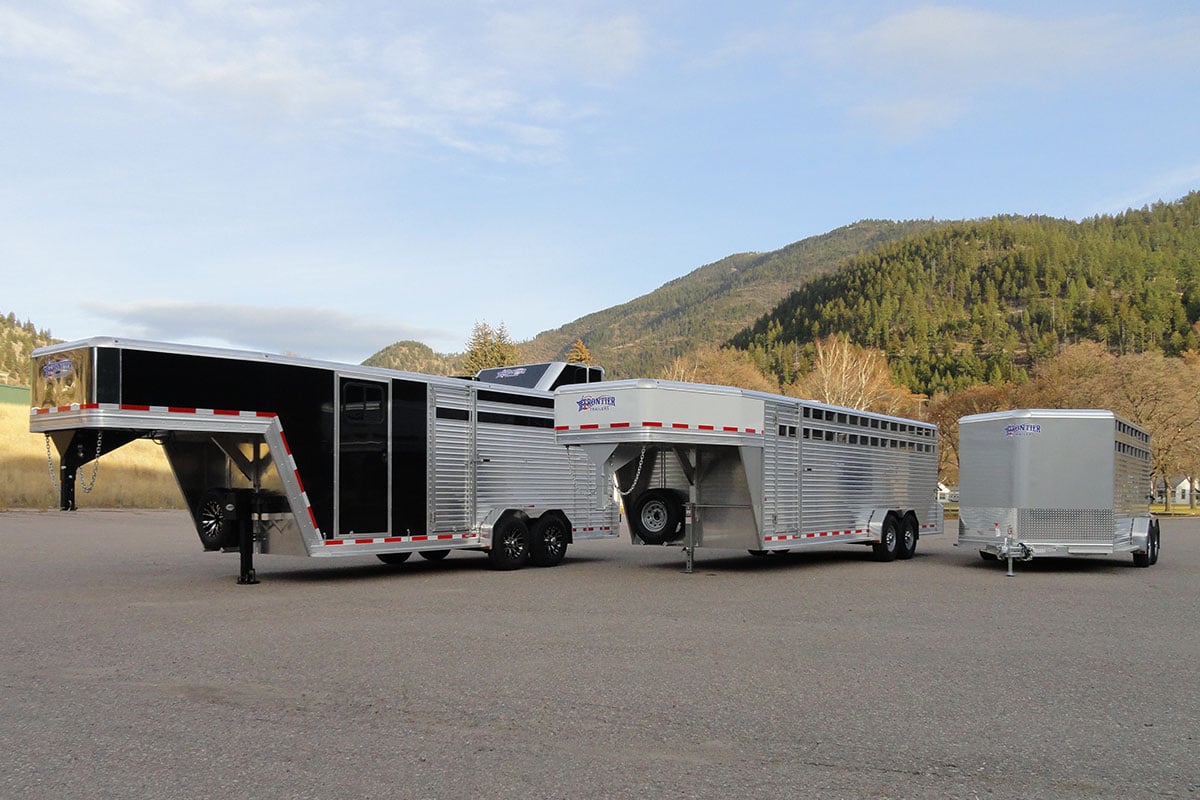 Three livestock trailers by Frontier in various sizes parked in front of mountains.