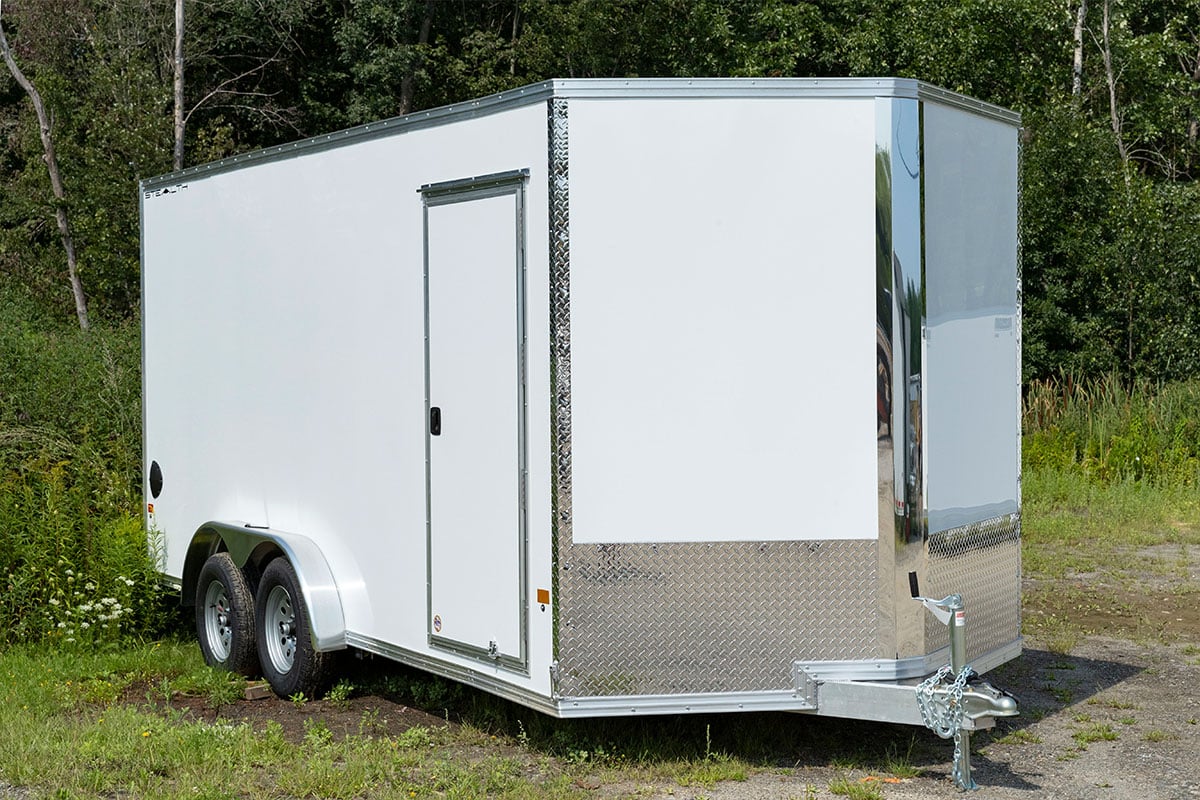 Enclosed V-nose aluminum cargo trailer by ALCOM parked with doors closed.