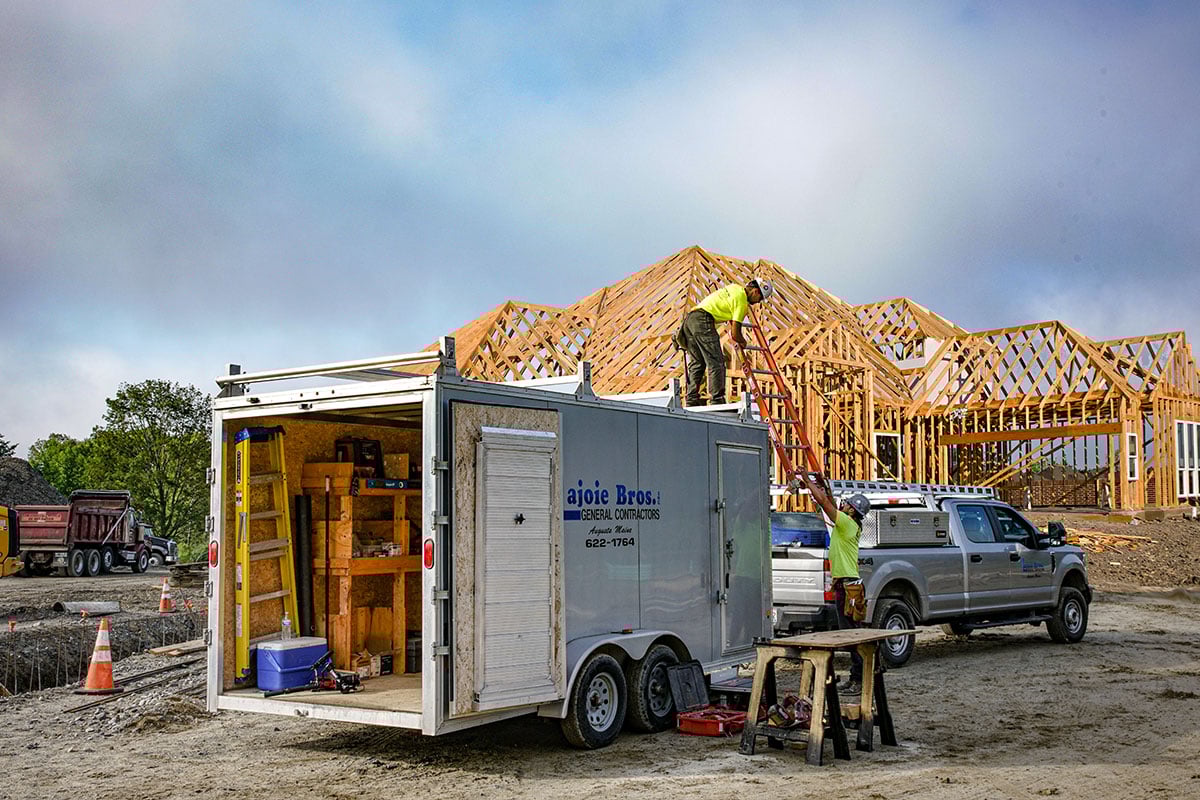 ALCOM enclosed contractor trailer, barn doors open on the jobsite, worker using catwalk system