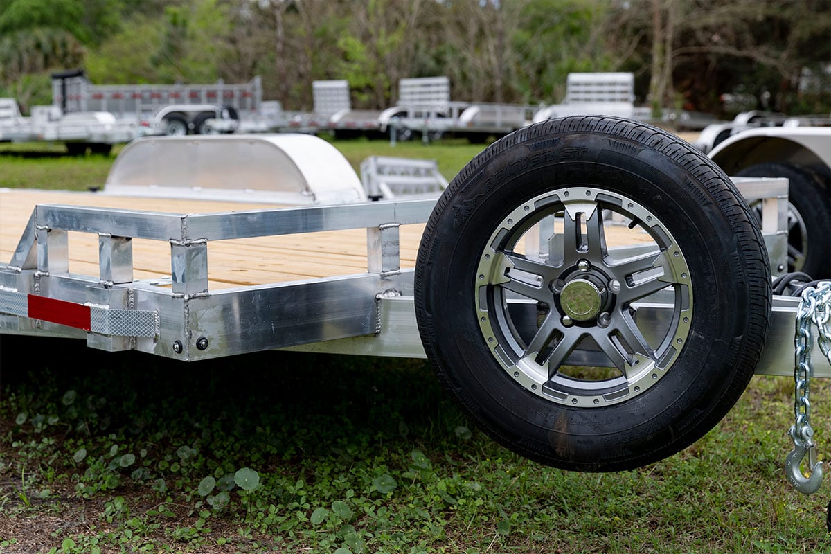 Open aluminum utility trailer with spare tire.