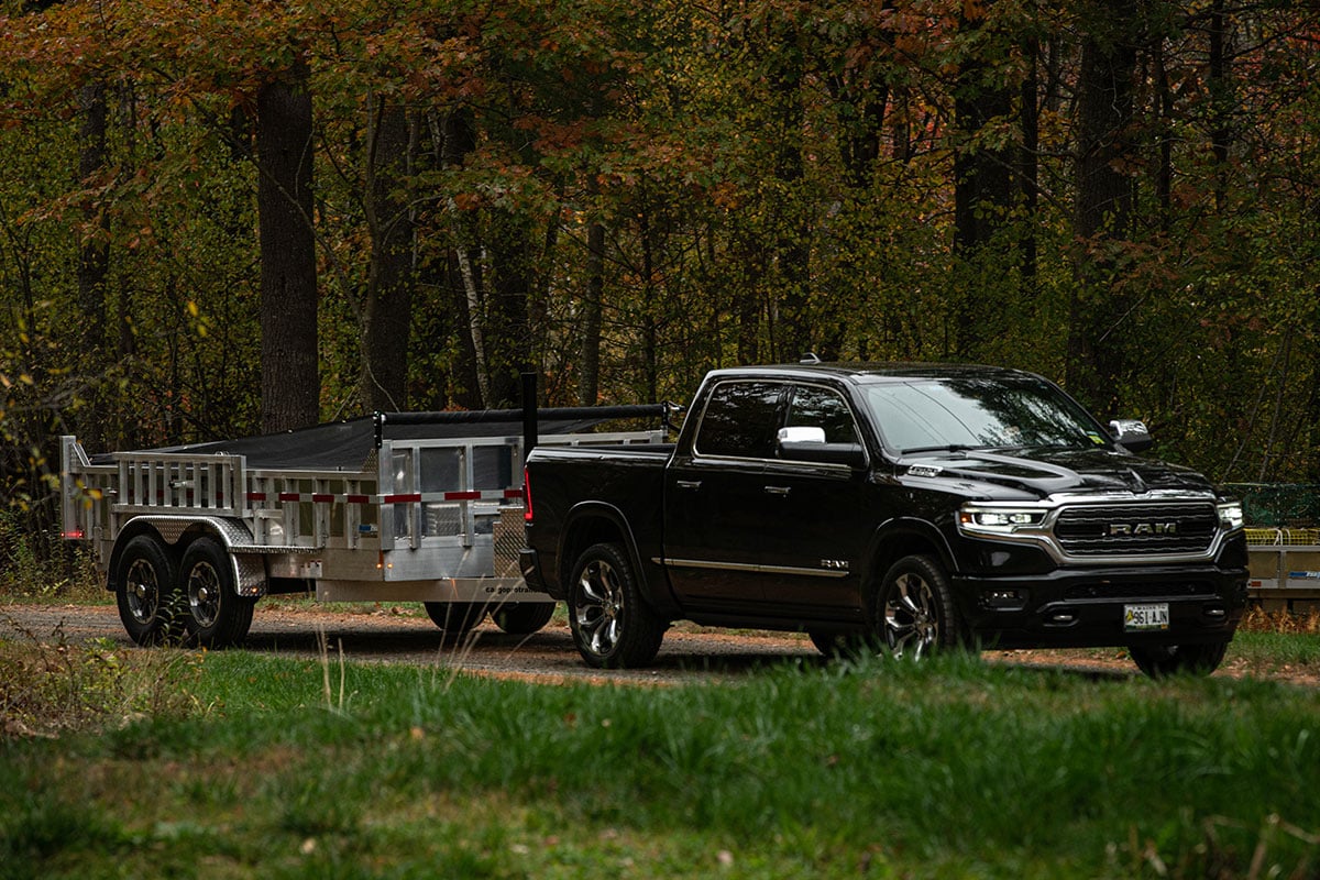ALCOM commercial dump trailer on the way to a jobsite towed by a pickup
