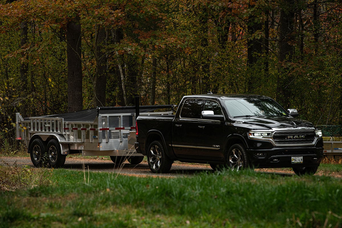 ALCOM commercial dump trailer on the way to a jobsite towed by a pickup