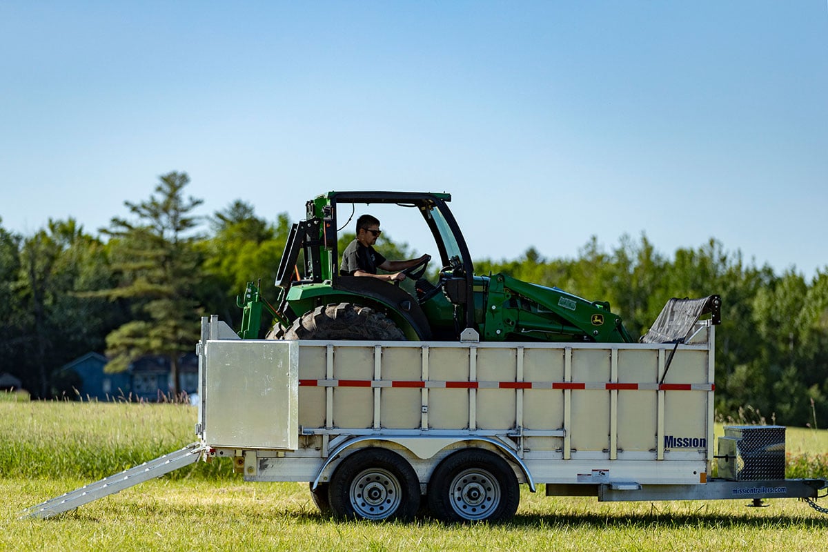 Tractor loaded into an ALCOM commercial dump trailer using ramps