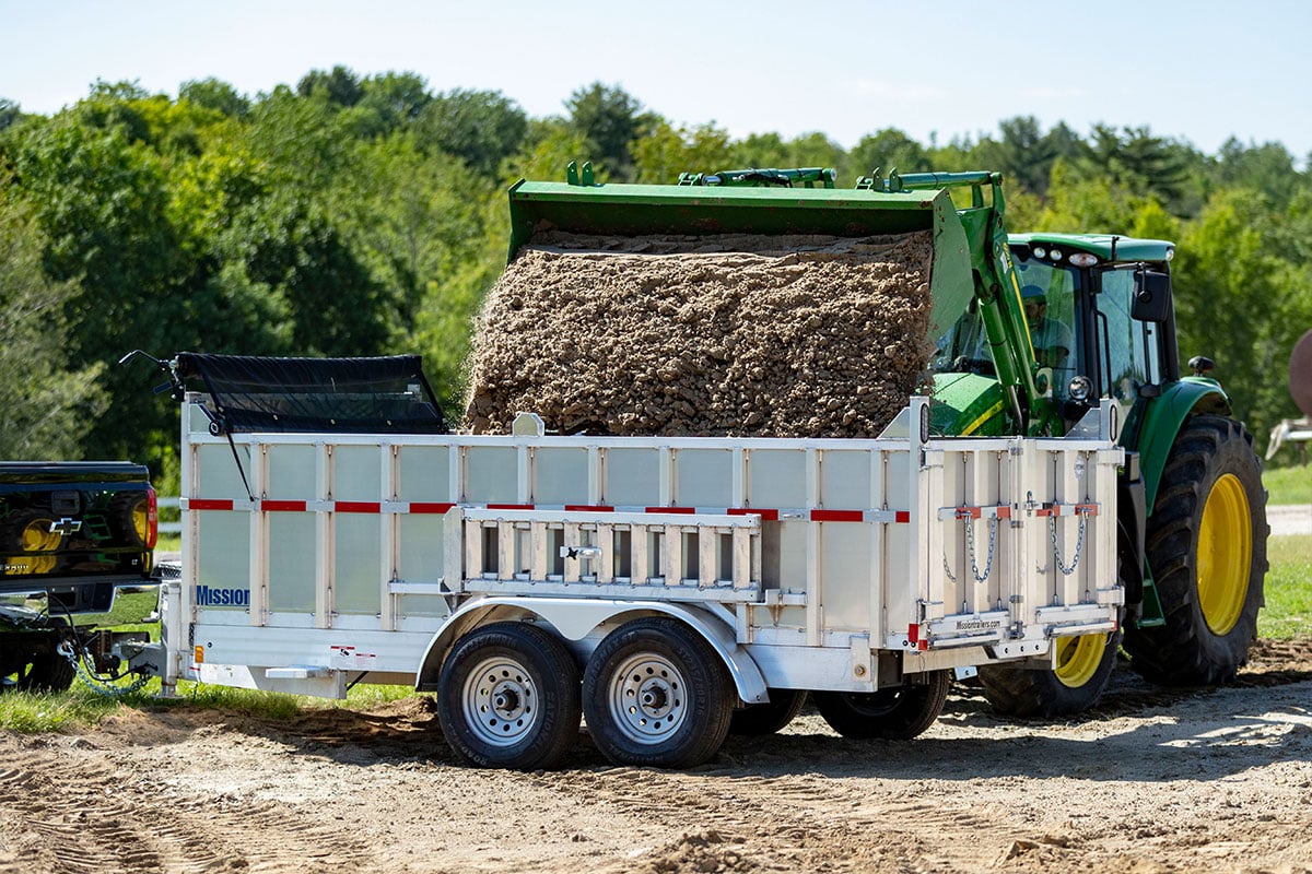 Loading dirt into an ALCOM commercial dump trailer