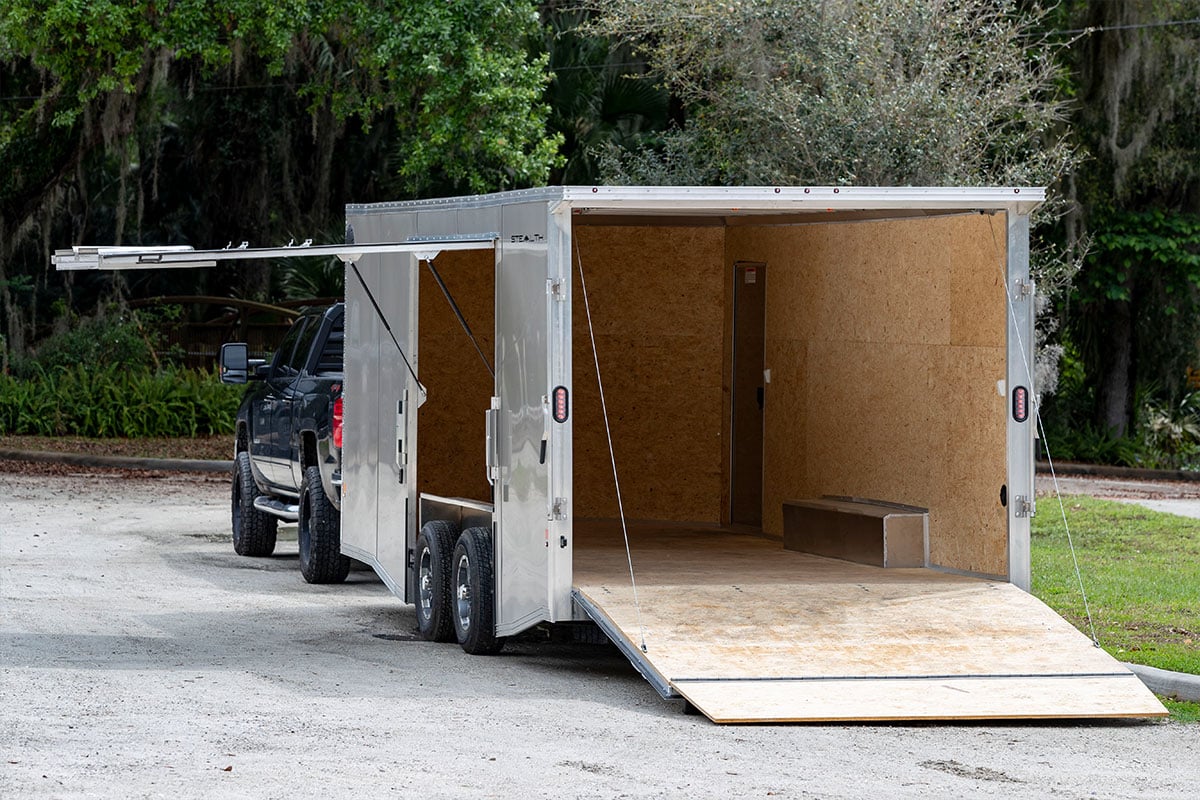 Enclosed car hauler by ALCOM, with rear and escape doors open