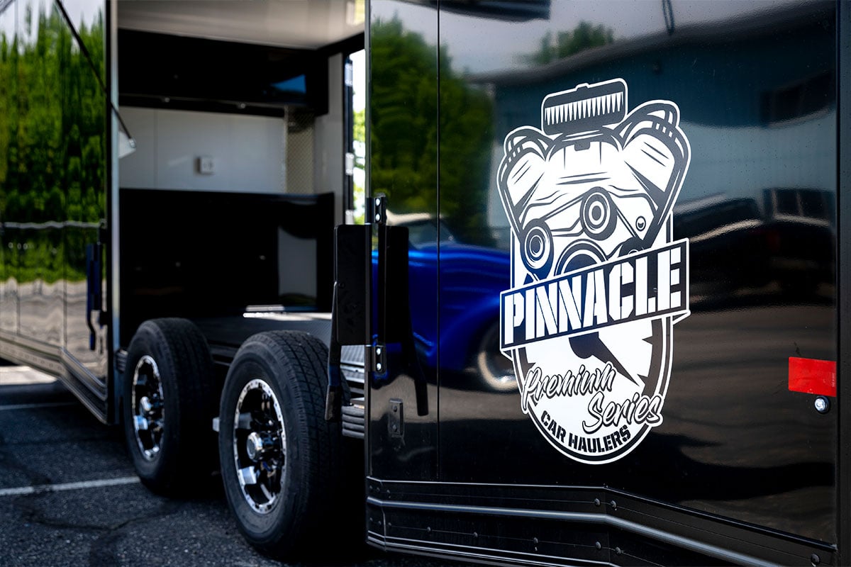 An enclosed Pinnacle series aluminum car hauler from ALCOM with the elite escape door open