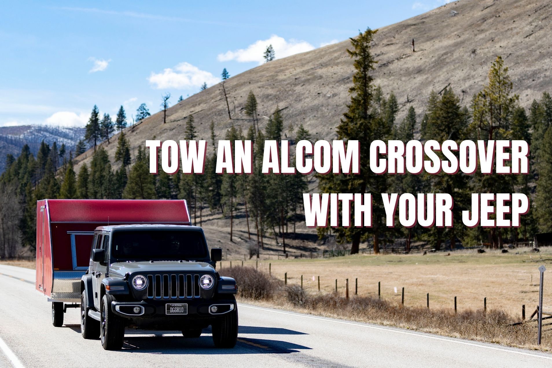 A gray Jeep SUV tows a red High Country aluminum crossover snow trailer on a Montana road with hills and trees in the background