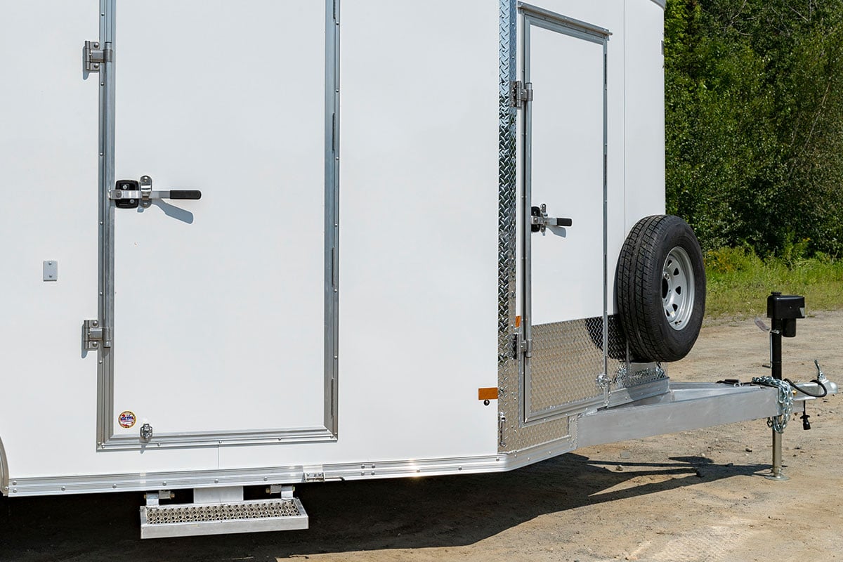 Enclosed aluminum ALCOM trailer with two side doors, each with locking bar over paddle handles 