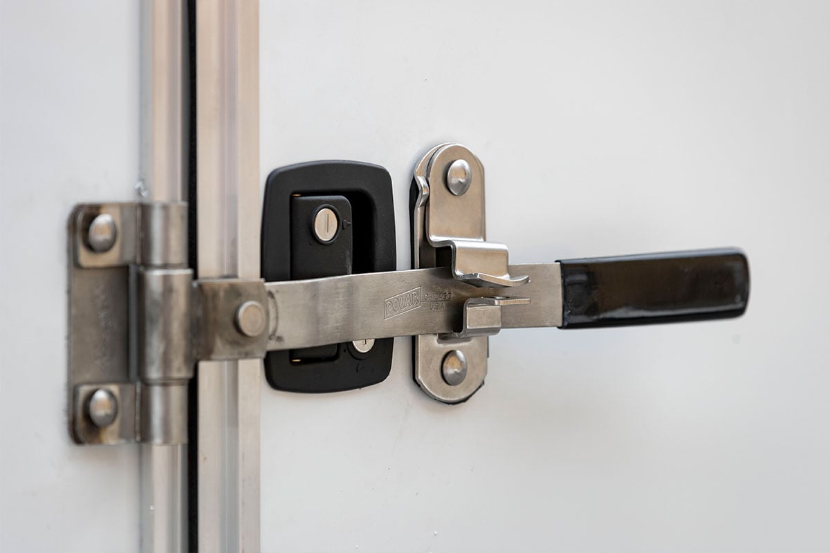 Close up view of locking bar over paddle handle on ALCOM enclosed aluminum trailer