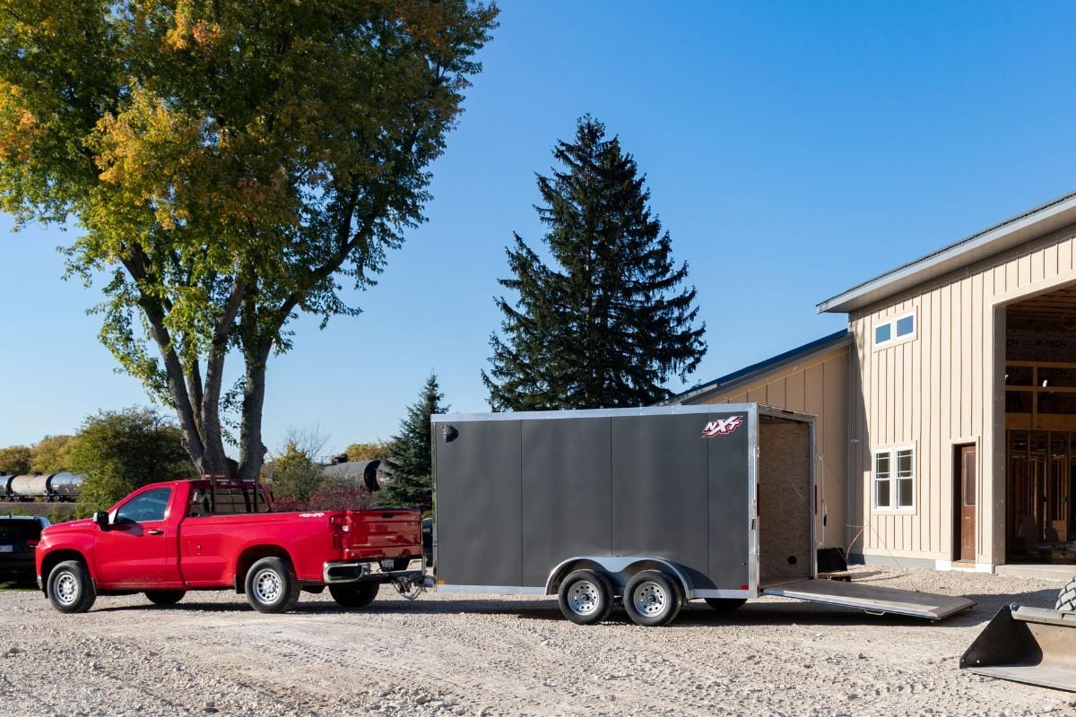 Gray enclosed aluminum cargo trailer hitched to red pickup