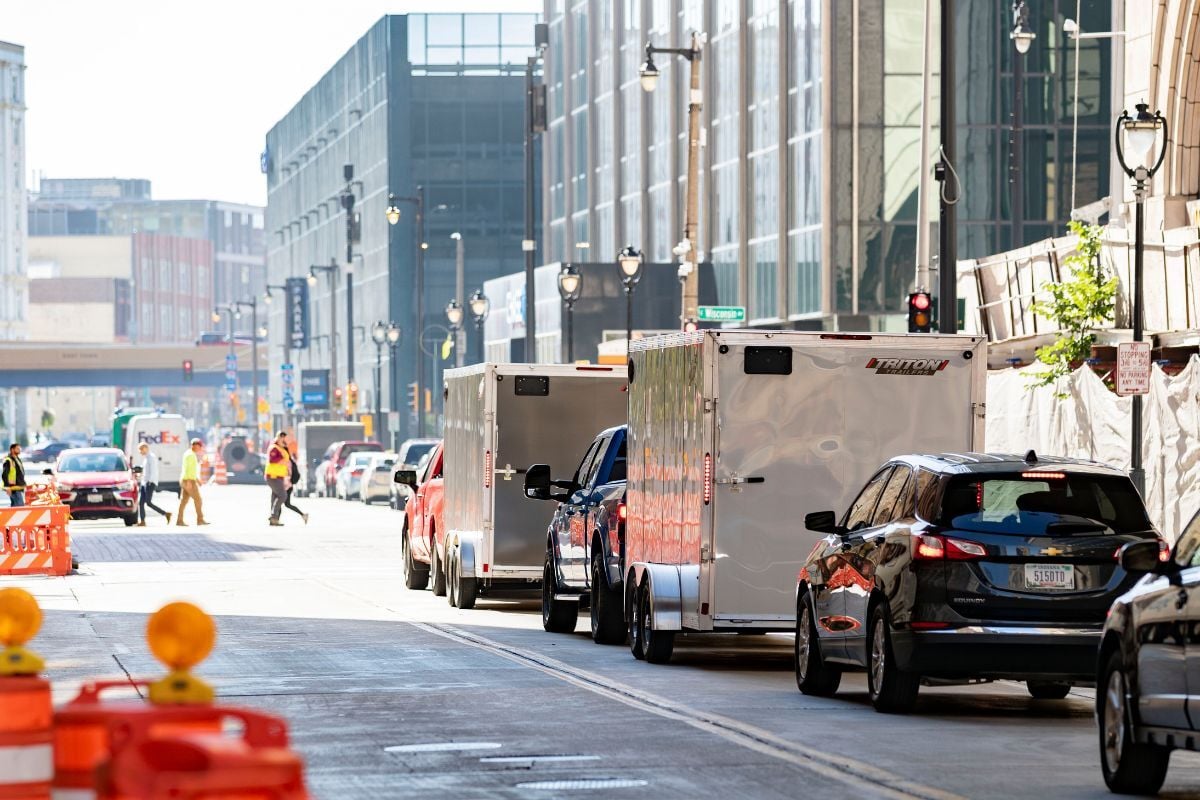 Two aluminum enclosed cargo trailers towed in a city