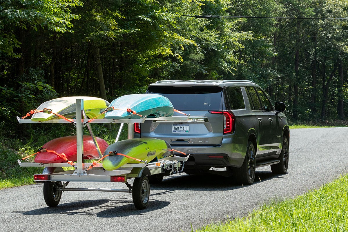 SUV towing an aluminum four-place kayak trailer by Triton Trailers