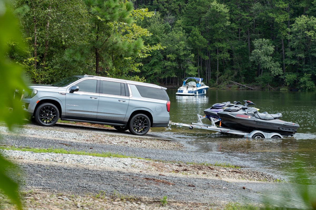 Gray SUV towing a Triton aluminum two-place PWC trailer out of the lake with PWCs loaded