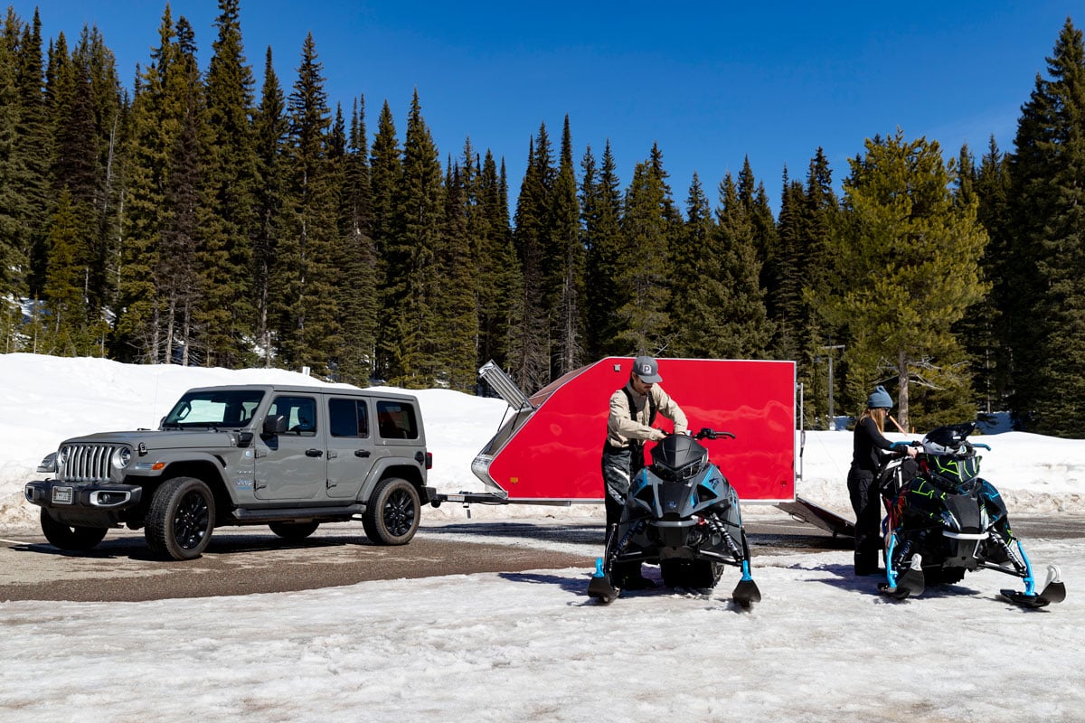 Red Crossover snowmobile trailer towed by a gray Jeep