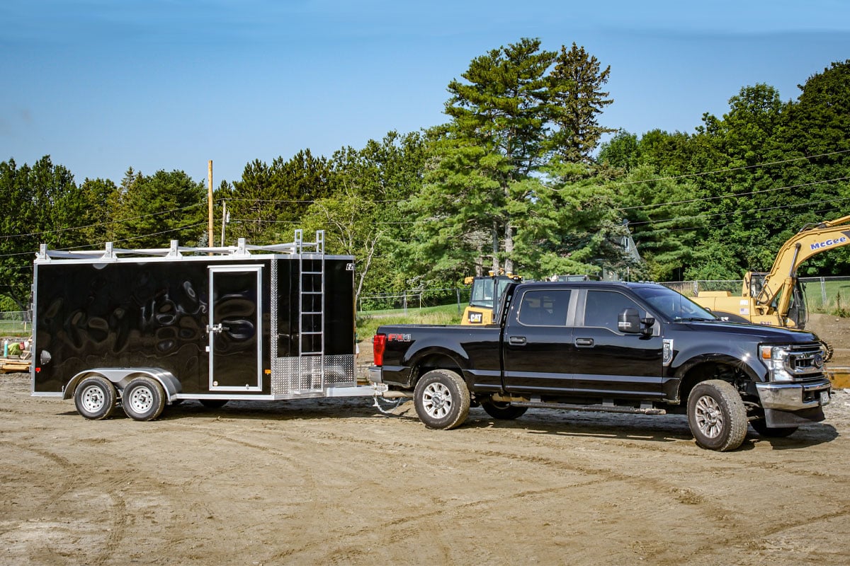 black-truck-hauling-black-ez-hauler-enclosed-ultimate-contractor-package-through-construction-site