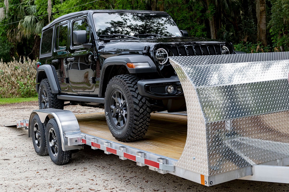 Jeep loading onto a wood deck ALCOM aluminum car trailer with diamond plate air dam
