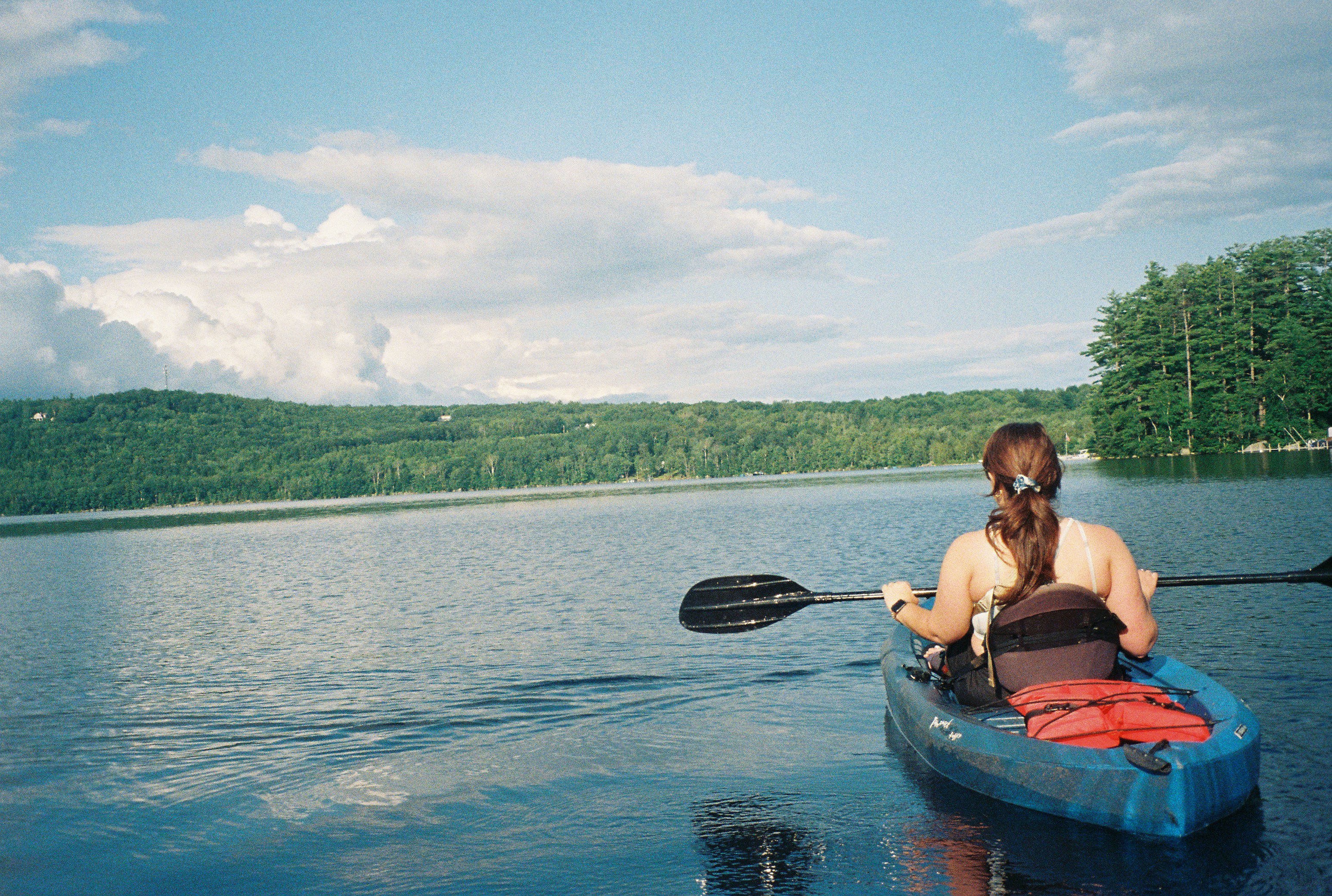A woman kayaking on a Maine lake - Photo by Carly Mackler