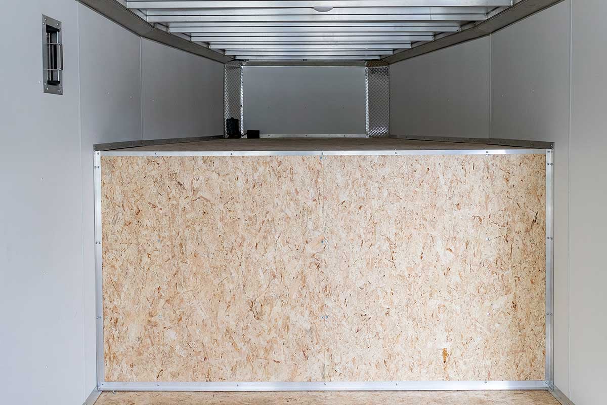 Interior view of the front of a gooseneck car hauler with wall panels, water resistant decking, and gooseneck attic