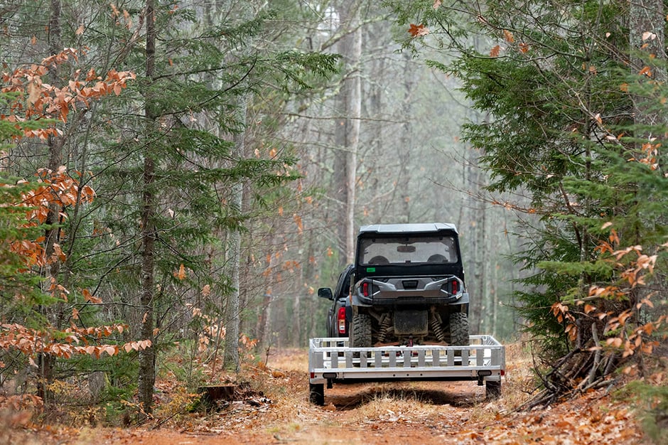 83" aluminum ATV trailer hauling a side by side on a wooded trail on a misty autumn morning