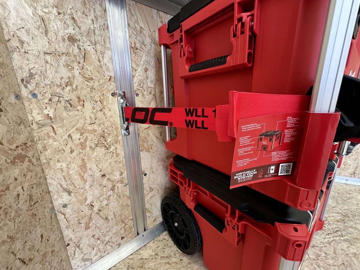 Tool boxes secured to the trailer wall with cargo straps that use the integrated wall studs as anchor points