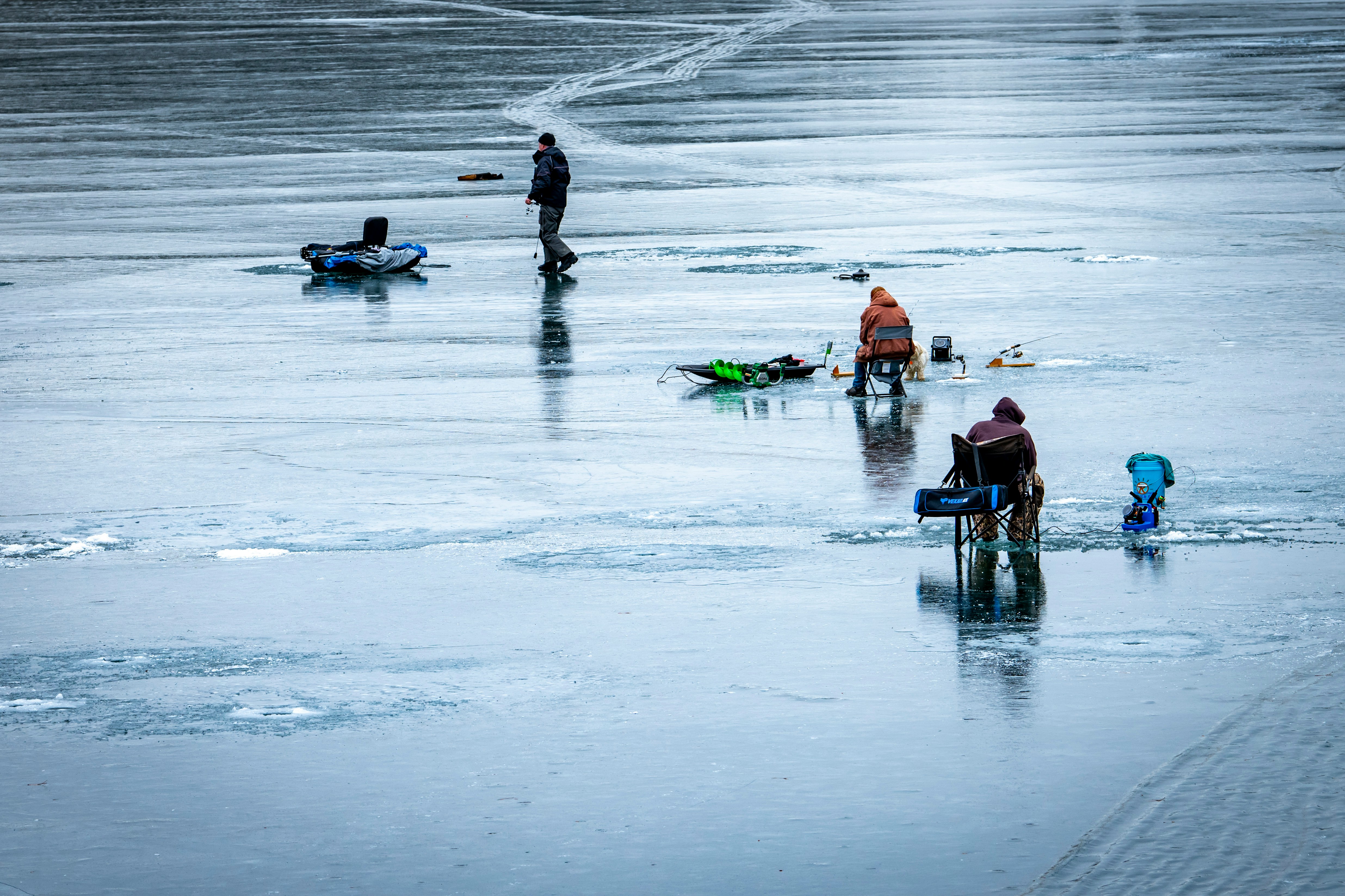 Multiple people ice fishing on a frozen lake; photo credit: Jon Sailer via Unsplash